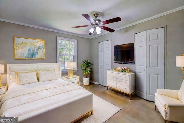 bedroom featuring multiple closets, light hardwood / wood-style flooring, ceiling fan, and ornamental molding