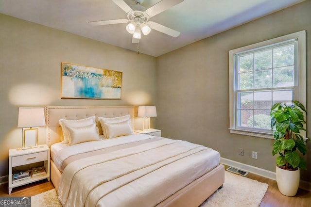 bedroom featuring multiple windows, wood-type flooring, and ceiling fan