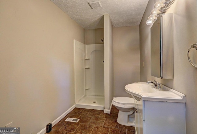 bathroom featuring toilet, vanity, a textured ceiling, and walk in shower