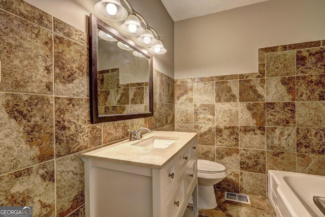 bathroom featuring vanity, toilet, and tile walls