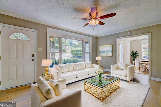 living room with a textured ceiling, light hardwood / wood-style flooring, and ceiling fan