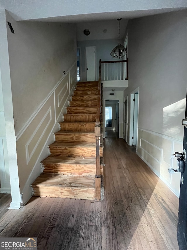 stairs featuring hardwood / wood-style floors and a chandelier