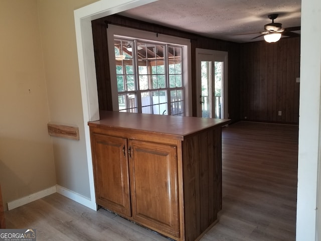 kitchen featuring kitchen peninsula, light wood-type flooring, ceiling fan, and a textured ceiling