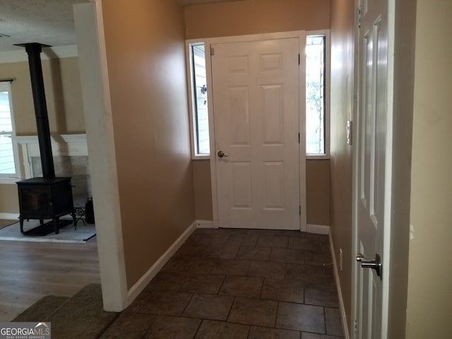 entryway with dark wood-type flooring and a wood stove