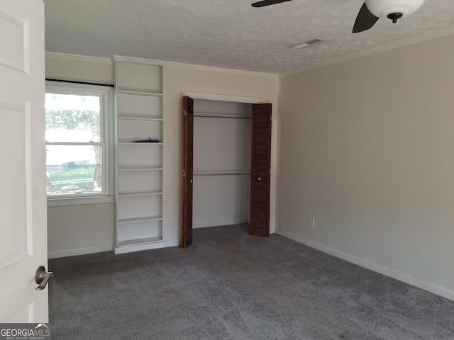 unfurnished bedroom with ceiling fan, ornamental molding, a textured ceiling, a closet, and dark colored carpet