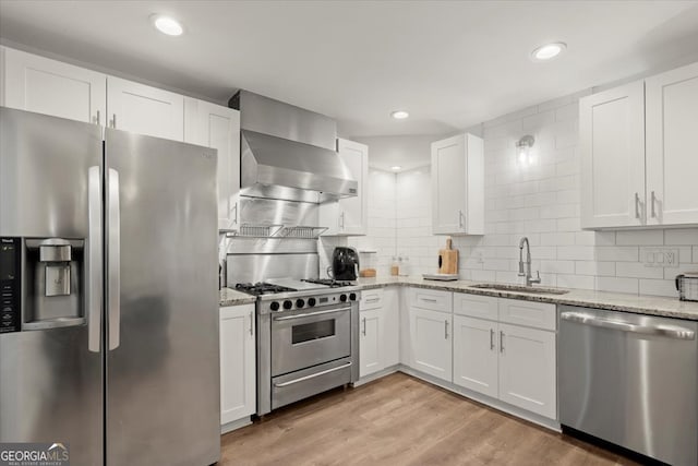 kitchen with appliances with stainless steel finishes, white cabinetry, sink, and light hardwood / wood-style floors