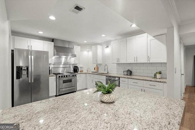 kitchen featuring light stone countertops, hardwood / wood-style floors, stainless steel appliances, white cabinets, and sink