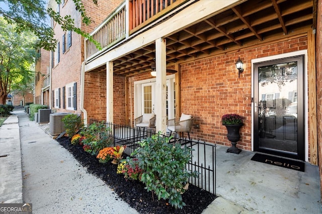 view of exterior entry with a balcony and central AC