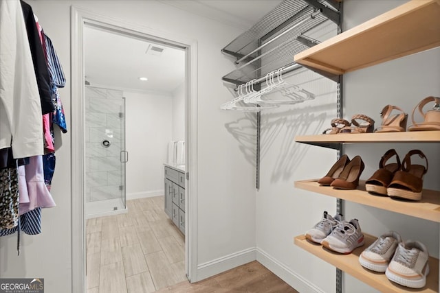 walk in closet with light hardwood / wood-style flooring