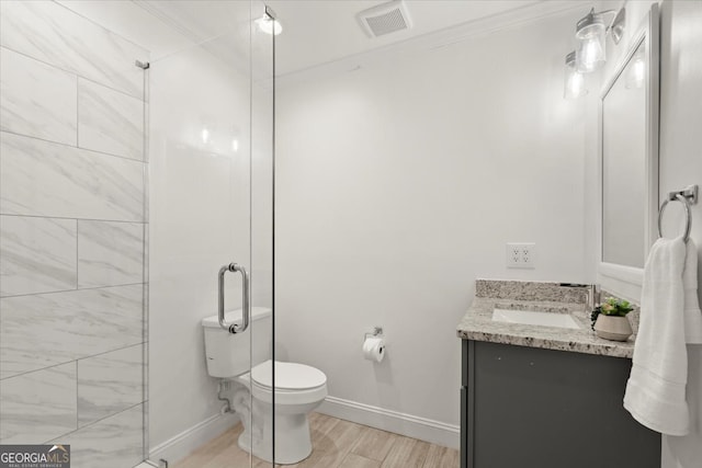 bathroom featuring vanity, toilet, ornamental molding, hardwood / wood-style floors, and a shower with door