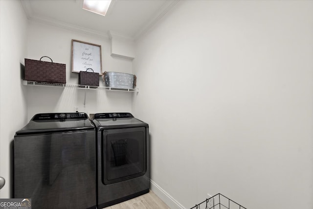 clothes washing area with crown molding, independent washer and dryer, and light hardwood / wood-style floors