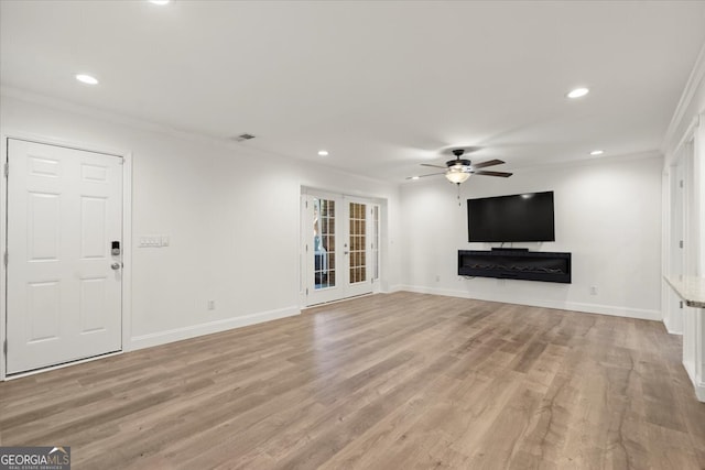 unfurnished living room with crown molding, ceiling fan, french doors, and light hardwood / wood-style flooring