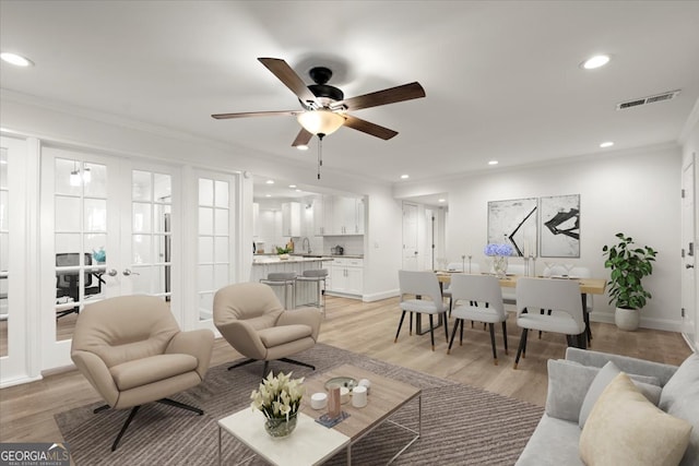 living room featuring ornamental molding, ceiling fan, french doors, and light hardwood / wood-style flooring