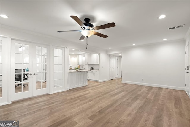 unfurnished living room featuring ceiling fan, sink, ornamental molding, french doors, and light hardwood / wood-style flooring