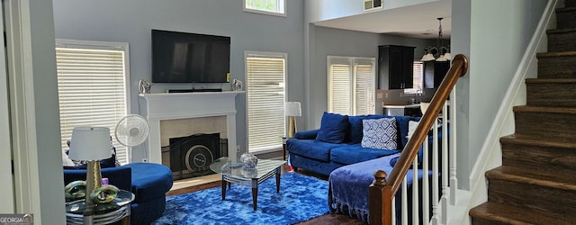 living room featuring dark wood-type flooring, a notable chandelier, and a towering ceiling