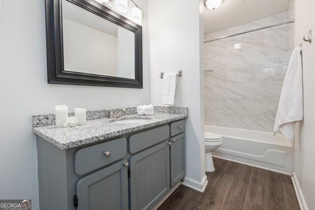 full bathroom featuring vanity, hardwood / wood-style floors, tiled shower / bath combo, and toilet