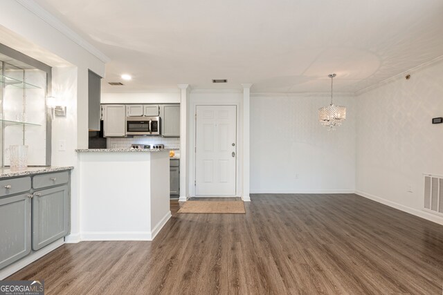 kitchen featuring gray cabinetry, light stone countertops, backsplash, dark hardwood / wood-style flooring, and hanging light fixtures