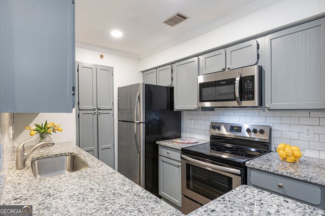 kitchen with sink, crown molding, gray cabinets, appliances with stainless steel finishes, and light stone counters