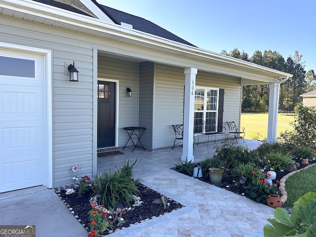 view of exterior entry featuring a garage and a porch