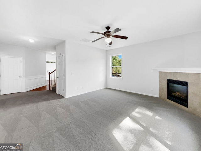 unfurnished living room with a fireplace, ceiling fan, and carpet