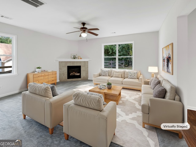 carpeted living room featuring ceiling fan and a tiled fireplace