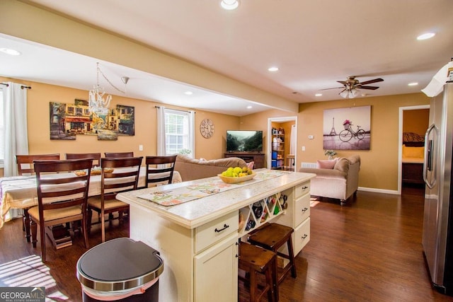 kitchen with ceiling fan, a center island, dark wood-type flooring, decorative light fixtures, and stainless steel refrigerator with ice dispenser