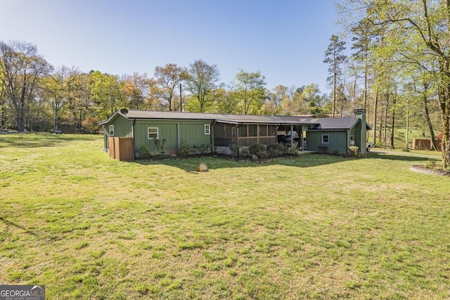 rear view of house with a yard and a sunroom