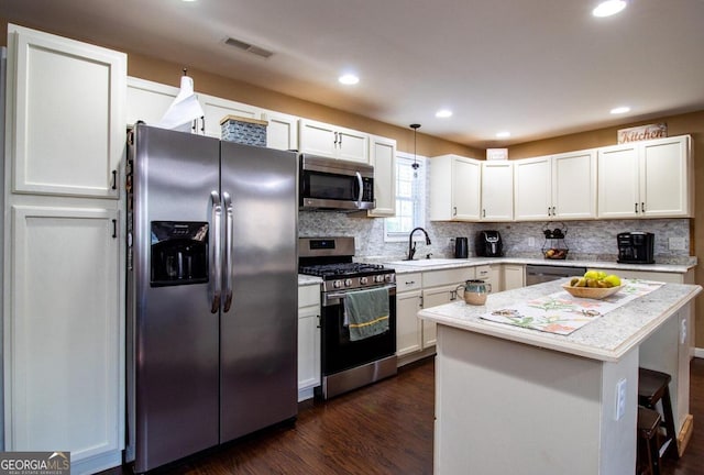 kitchen with dark hardwood / wood-style flooring, sink, stainless steel appliances, white cabinets, and a center island