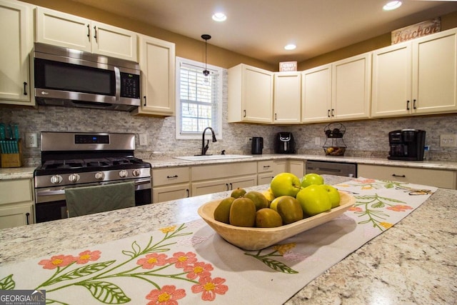 kitchen with decorative backsplash, light stone countertops, appliances with stainless steel finishes, and sink