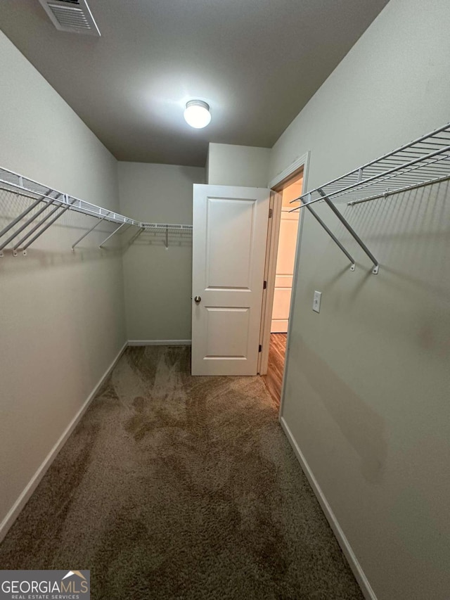 walk in closet featuring dark colored carpet