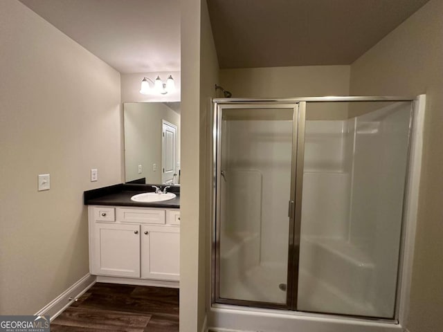 bathroom featuring wood-type flooring, a shower with door, and vanity