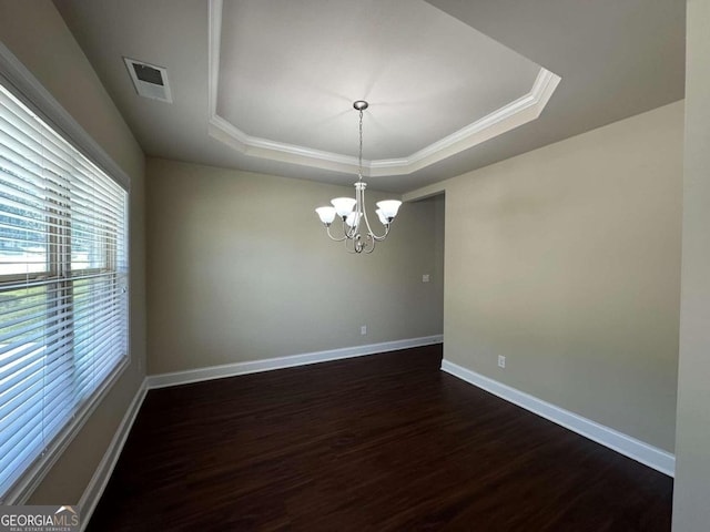 empty room with dark wood-type flooring, a raised ceiling, and a chandelier