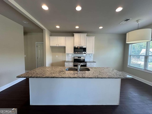 kitchen featuring light stone countertops, white cabinets, appliances with stainless steel finishes, and a kitchen island with sink