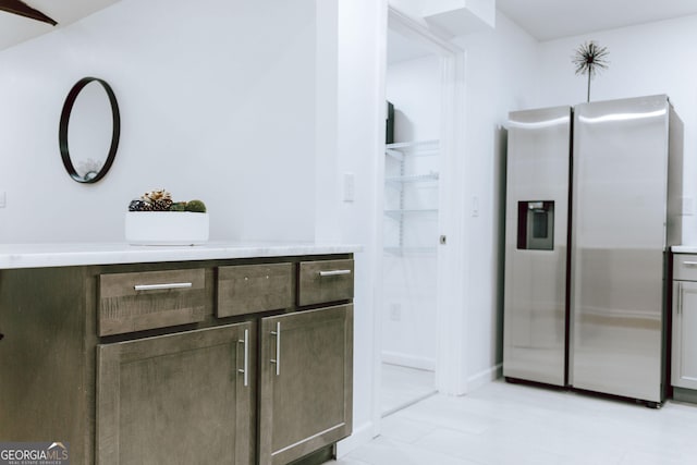 kitchen featuring stainless steel refrigerator with ice dispenser and dark brown cabinetry