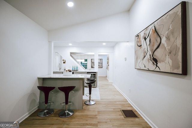 corridor with lofted ceiling, sink, and light wood-type flooring