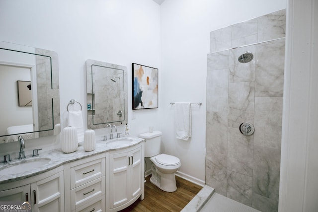 bathroom featuring vanity, wood-type flooring, toilet, and tiled shower