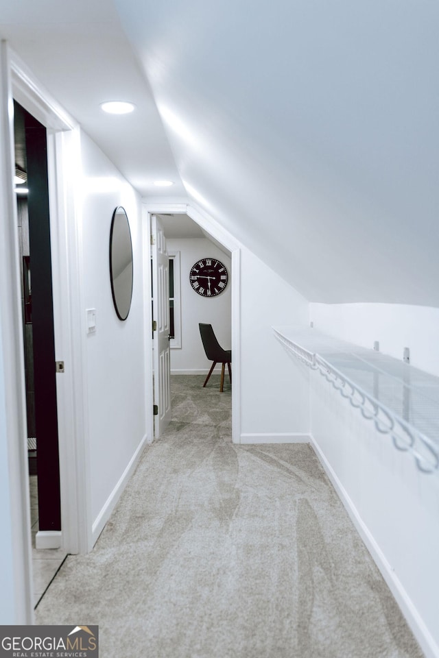 corridor featuring light colored carpet and vaulted ceiling