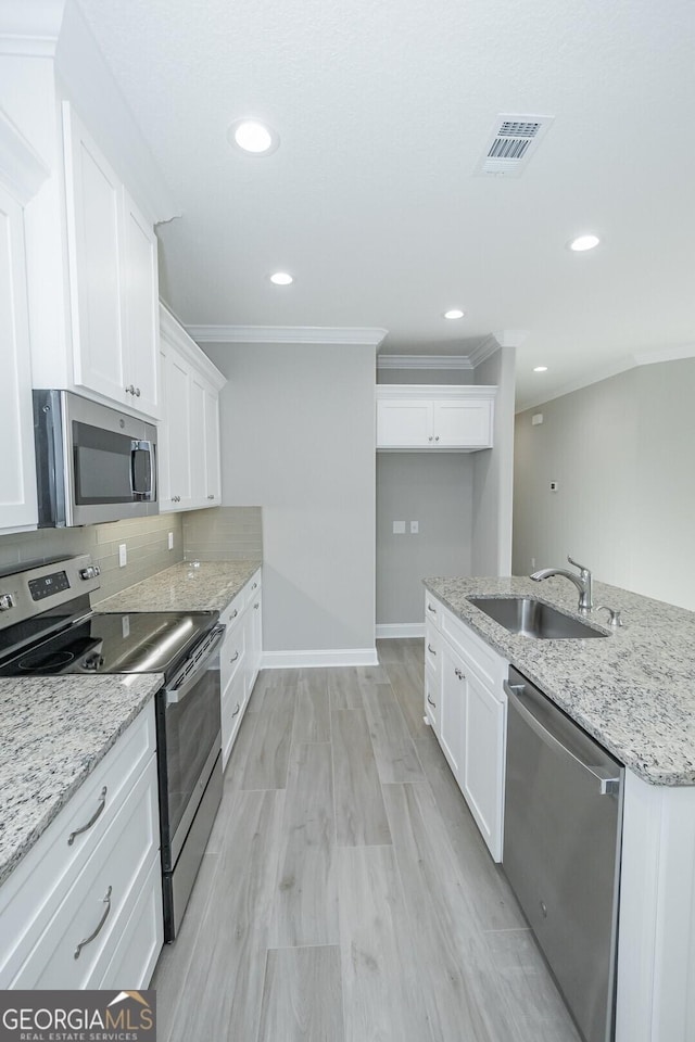 133 Amanda Trce, Kingsland, GA 31548 - kitchen featuring stainless steel appliances, ornamental molding, white cabinets, recessed lighting, and light stone counters