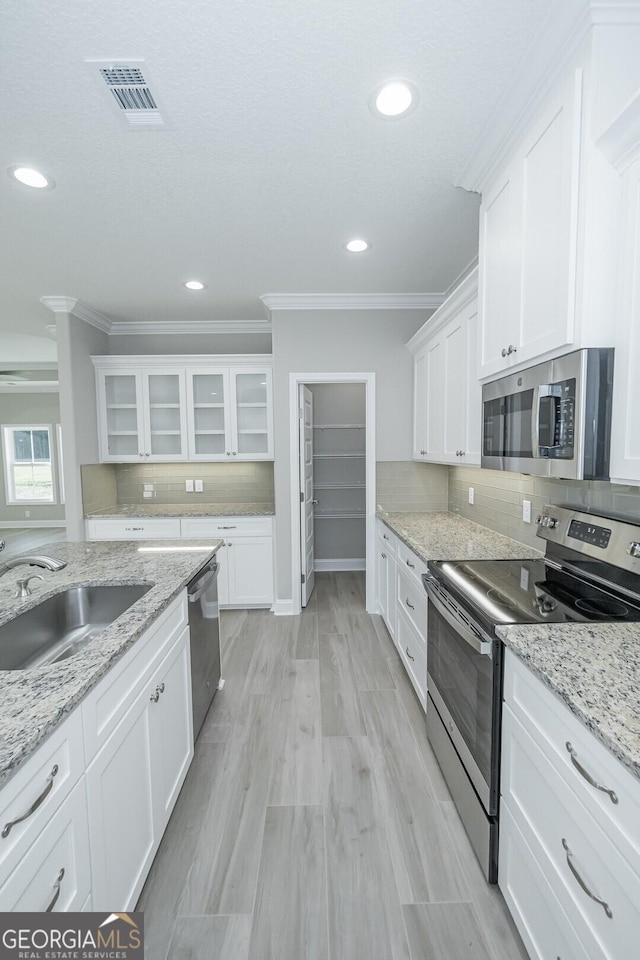 133 Amanda Trce, Kingsland, GA 31548 - kitchen featuring stainless steel appliances, crown molding, white cabinetry, glass insert cabinets, and tasteful backsplash