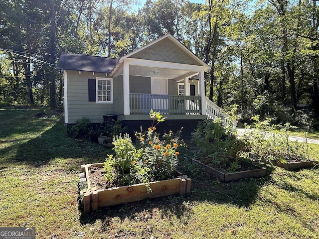 bungalow-style house with a garden, covered porch, and a front lawn