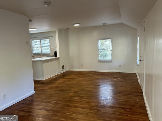 unfurnished room featuring vaulted ceiling, visible vents, dark wood-style flooring, and baseboards