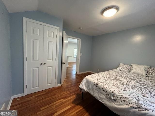 bedroom featuring dark wood-type flooring, baseboards, and a closet