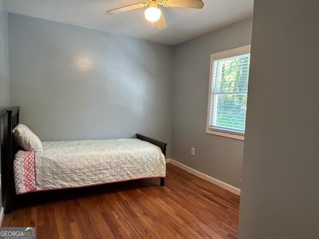 bedroom featuring baseboards, wood finished floors, and a ceiling fan