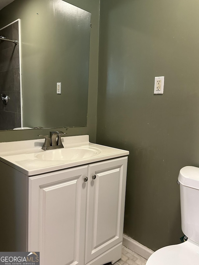 bathroom featuring baseboards, toilet, and vanity