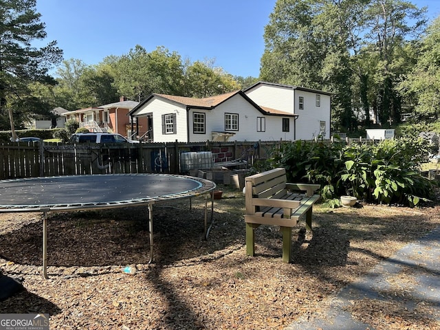 rear view of property with a trampoline and fence