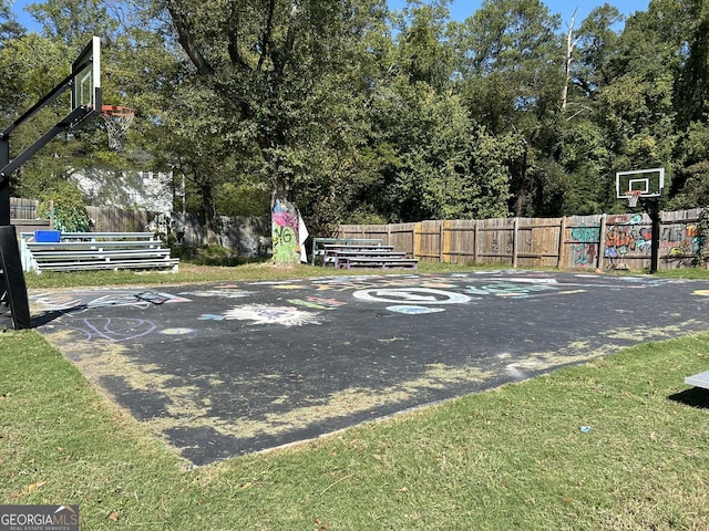 view of basketball court with basketball hoop and fence