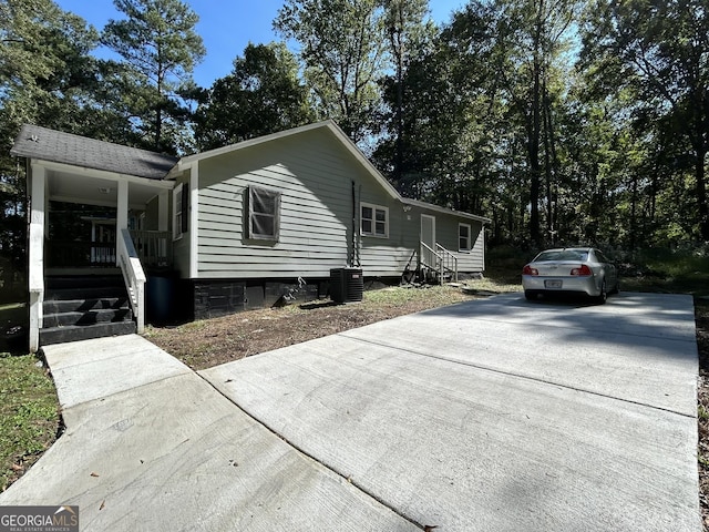 view of front of house featuring central air condition unit, covered porch, and concrete driveway