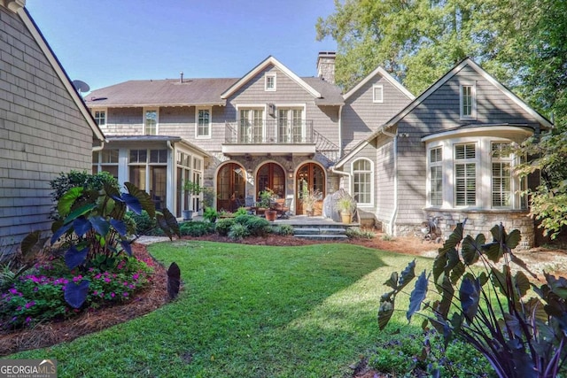 back of house with a yard and a balcony