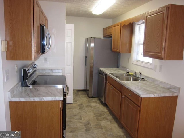 kitchen with a textured ceiling, stainless steel appliances, and sink