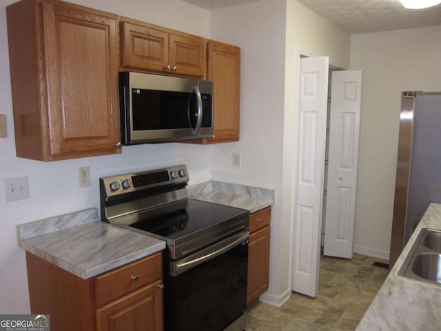 kitchen with a textured ceiling and appliances with stainless steel finishes